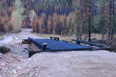 Looking east across the burned wooden bridge crossing Morrell Creek on FR 4381 on the way to Morrell Falls trailhead and Pyramid Pass trailhead as it appeared 10/11/17.  The bridge and forest have sustained heavy damage in the Rice Ridge fire.