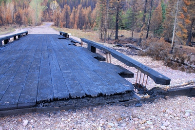 Looking east across the burned wooden bridge crossing Morrell Creek on FR 4381 on the way to Morrell Falls trailhead and Pyramid Pass trailhead as it appeared 10/11/17.  The bridge and forest have sustained heavy damage in the Rice Ridge fire.
