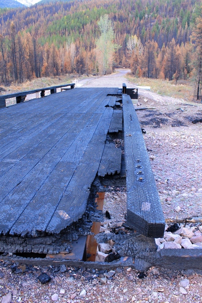 Looking east across the burned wooden bridge crossing Morrell Creek on FR 4381 on the way to Morrell Falls trailhead and Pyramid Pass trailhead as it appeared 10/11/17.  The bridge and forest have sustained heavy damage in the Rice Ridge fire. Morrell Creek below is dry.