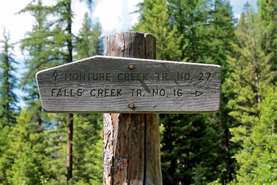 Old wooden sign after the bridge.  Monture Creek Trail (27) straight ahead and the Falls Creek Trail (16) to the right.